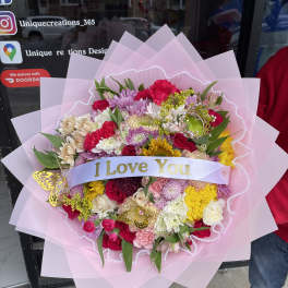 Large mixed flower bouquet wrapped in pink paper with an "I Love You" ribbon