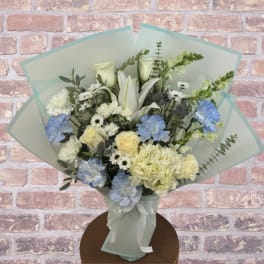 Bouquet of white and blue flowers wrapped in pale blue paper