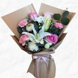 Bouquet of pink and white flowers wrapped in brown paper with a ribbon