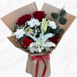 Bouquet of red roses, white lilies, and white carnations wrapped in brown paper