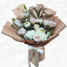 Bouquet of pale roses and white blooms wrapped in tan paper