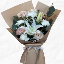Bouquet of white and blush flowers wrapped in tan paper