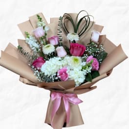 Bouquet of pink and white roses with hydrangeas wrapped in tan paper