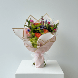 Bouquet of orange, pink, and purple flowers wrapped in pale pink paper