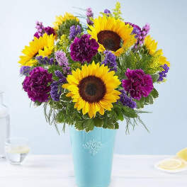 Sunflowers and purple flowers arranged in a blue vase