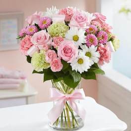Pink and white mixed bouquet in a glass vase with a pink ribbon