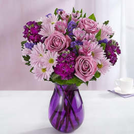 Lavender and purple mixed bouquet with roses and daisies in a purple glass vase