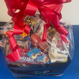 Gift basket of assorted snacks wrapped in clear cellophane with a large red bow