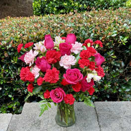 Pink roses and red carnations arranged in a glass vase