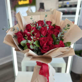 Bouquet of red roses wrapped in beige paper with a red ribbon
