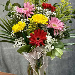 Bouquet of pink, red, and yellow gerbera daisies in a glass vase
