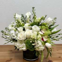 White and green floral arrangement in a black vase