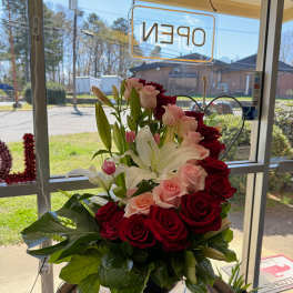 Bouquet of red and pink roses with white lilies in a black vase