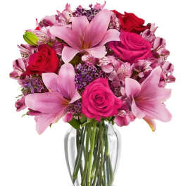Pink lilies and roses arranged in a clear glass vase