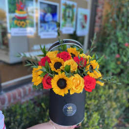Bouquet of red and yellow roses with sunflowers in a black hat box