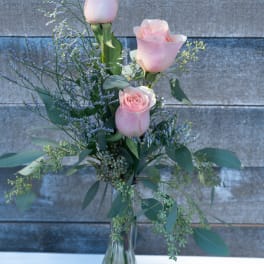 Pink roses in a clear glass vase with airy purple filler