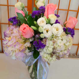 Bouquet of pink and white roses with purple flowers in a glass vase