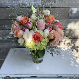 Mixed bouquet of roses, tulips, and hydrangeas in a glass vase