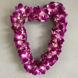Heart-shaped purple orchid lei hanging on a wall