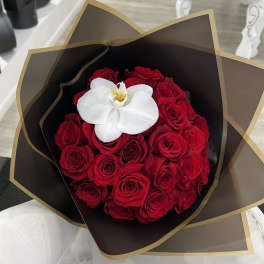 Bouquet of red roses with a white orchid in dark wrap