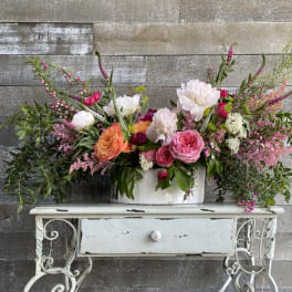 Large mixed floral arrangement in a white container on a small table