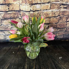 Tulip bouquet in a clear glass vase with pink, yellow, and white blooms.