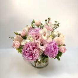 Low pink and white arrangement with peonies, tulips, and lisianthus in a clear glass vase