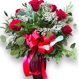 One dozen red roses in a ceramic red vase.