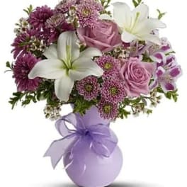 Pink and white bouquet in a lavender vase with a ribbon