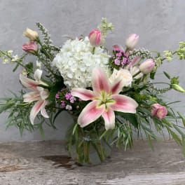 Pink and white lily bouquet in a glass vase with white hydrangea