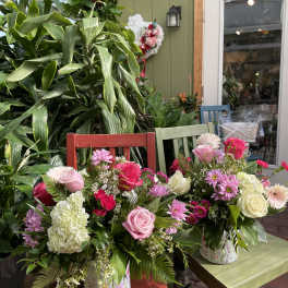 Two mixed flower arrangements in patterned containers on colorful chairs.