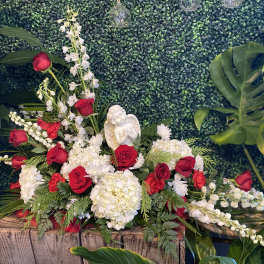 Red roses and white flowers arranged around a small angel figurine