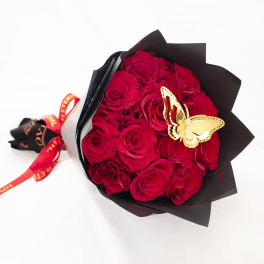 Bouquet of red roses wrapped in black paper with a butterfly decoration