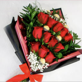 Bouquet of red roses with gold-wrapped chocolates and white filler flowers
