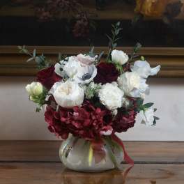 Bouquet of red and white flowers in a round glass vase