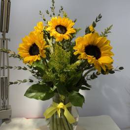 Sunflower bouquet in a glass vase with a yellow ribbon