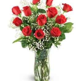 Red roses arranged in a clear glass vase with baby's breath