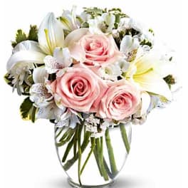 Pink roses and white lilies arranged in a clear glass vase