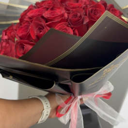 Bouquet of red roses wrapped in black paper with a pink ribbon