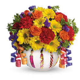 Colorful bouquet of roses, daisies, and carnations in a white vase with curling ribbons