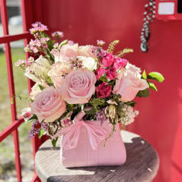 Pink and white rose bouquet in a pink handbag-style container