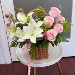 Basket arrangement of pink roses and white lilies