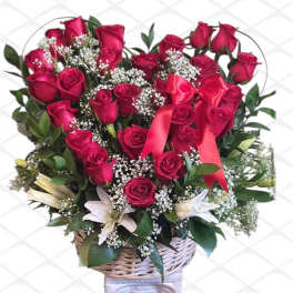 Red rose bouquet with white filler flowers in a wicker basket