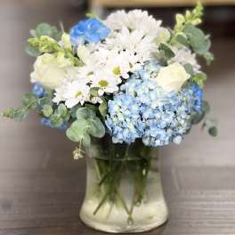 Blue hydrangeas and white daisies with roses in a glass vase