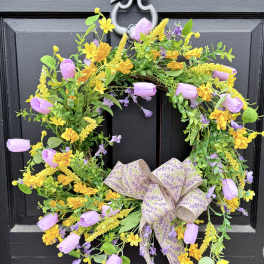 Floral wreath with purple and yellow blooms on a black door