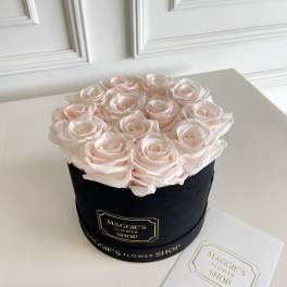 Pale pink roses arranged in a black round box