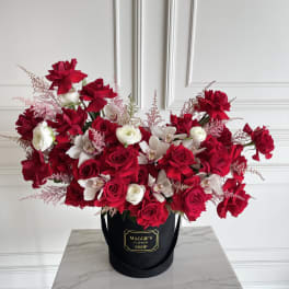 Red and white roses with orchids in a black hatbox