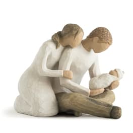 Three carved figures in white and tan, one holding a baby