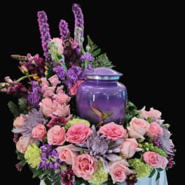 Pink and purple floral arrangement around a purple urn