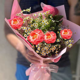 Pink bouquet with coral flowers and small white daisies wrapped in pink paper